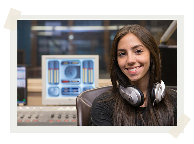 A student wearing headphones around her neck in a recording studio.